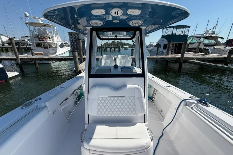 Slide: The Image of 2024 Sportsman Open 262 Center Console boat docked at marina, showcasing interior seating and helm. - 29
