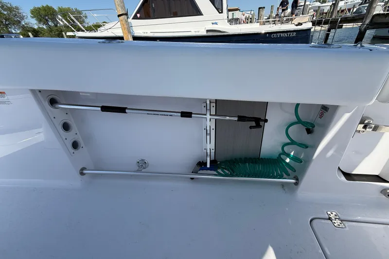 Slide: The Image of 2024 Sportsman Open 262 Center Console boat storage compartment with hose and rod holders. - 32