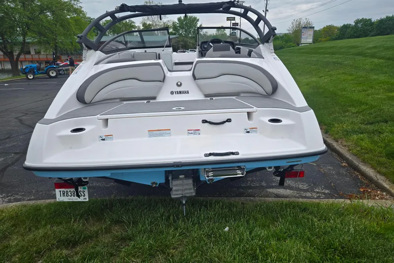 Slide: The Image of 2025 Yamaha Boats AR190, white exterior, parked on grass, rear view. - 2