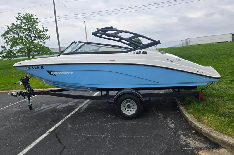 Slide: The Image of 2025 Yamaha AR190 boat on trailer, parked on asphalt near grassy area. - 4