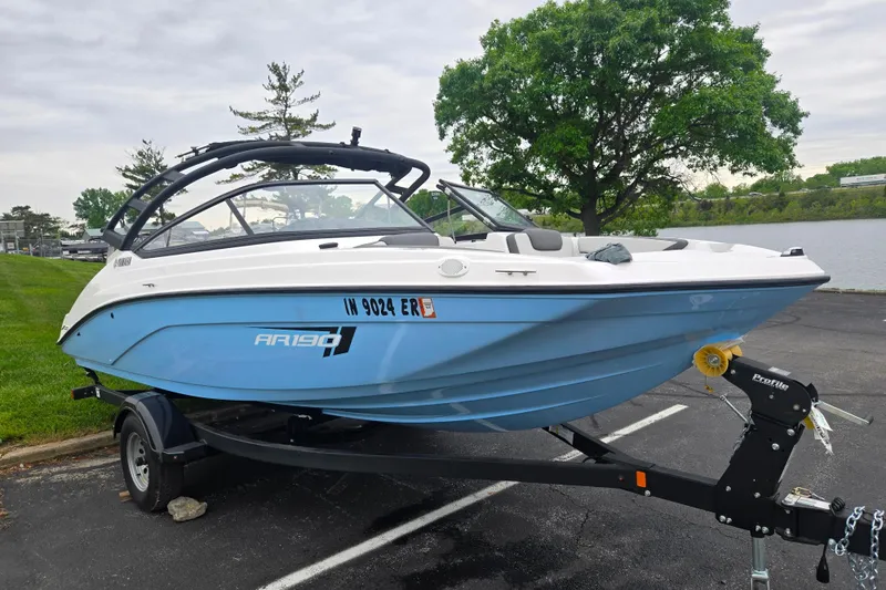 Slide: The Image of 2025 Yamaha Boats AR190 on trailer, parked near a lake with lush greenery. - 8
