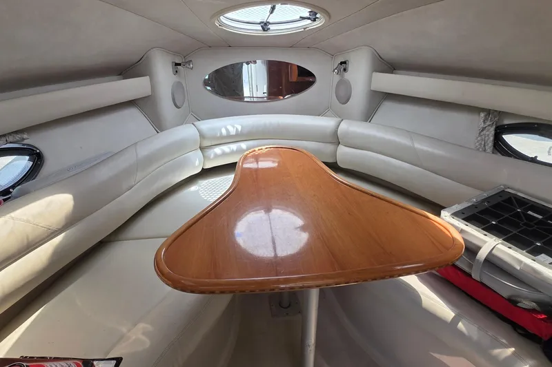 Slide: The Image of Interior of a 2001 Doral 250se boat with a wooden table and cushioned seating. - 10