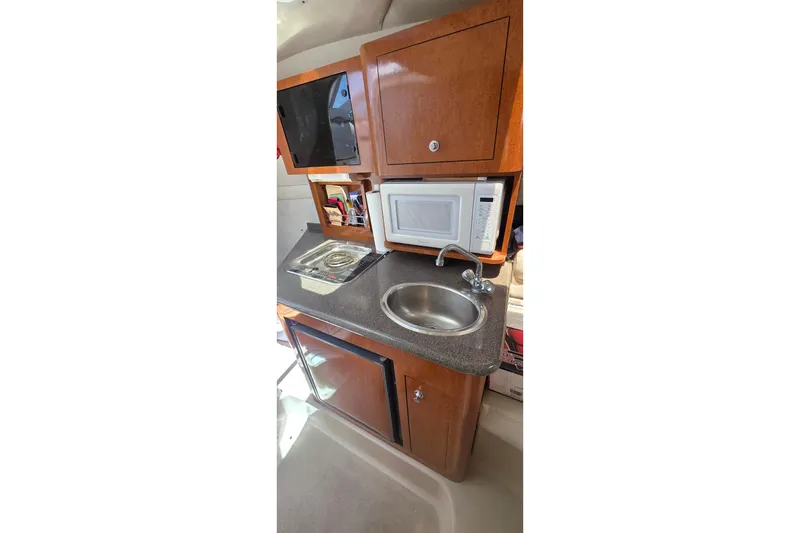 Slide: The Image of Compact kitchen area in a 2001 Doral 250se boat with sink, microwave, and stove. - 11