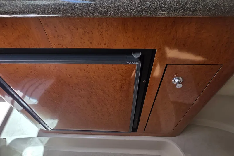 Slide: The Image of Wooden cabinet with Norcold fridge in 2001 Doral 250se boat interior. - 14