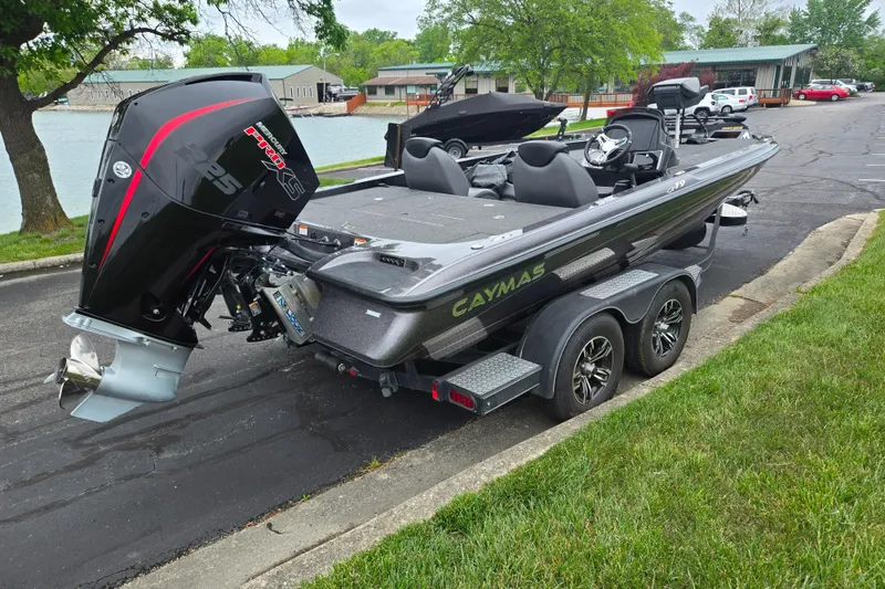 Slide: The Image of 2022 Caymas CX 19 boat on trailer, parked near a lake with trees and buildings. - 1