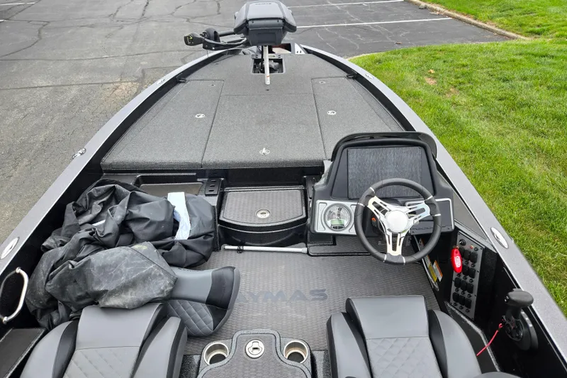 Slide: The Image of 2022 Caymas CX 19 boat interior with steering wheel and seating, parked on pavement. - 12
