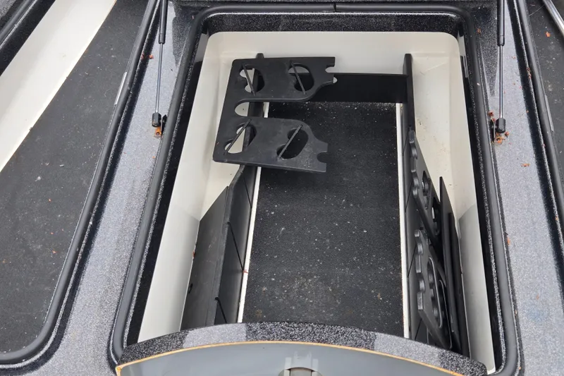 Slide: The Image of Open storage compartment in 2022 Caymas CX 19 boat, featuring rod holders and organized space. - 16