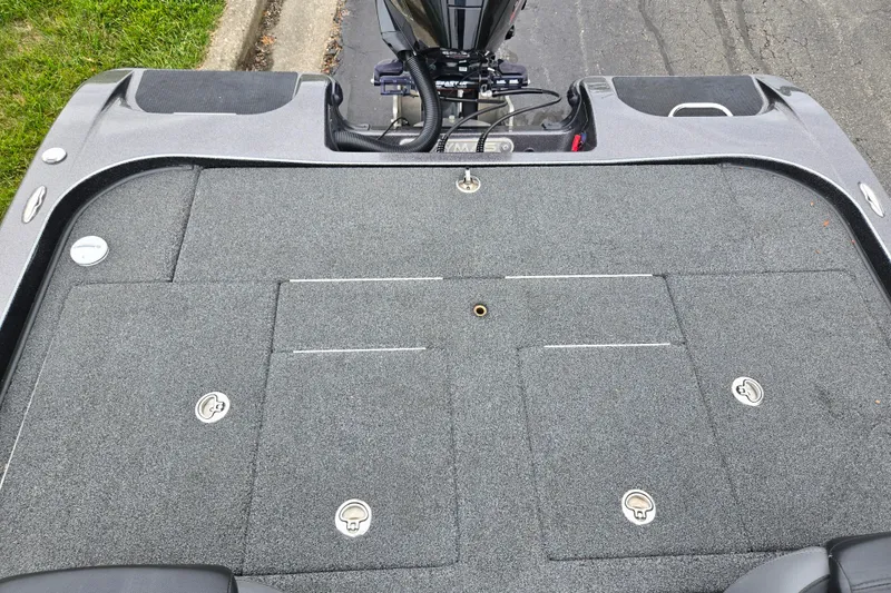 Slide: The Image of 2022 Caymas CX 19 boat deck with storage compartments and motor, parked on pavement. - 22