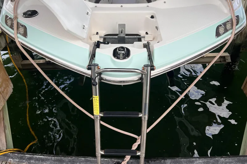 Slide: The Image of 2019 Chaparral 250 Suncoast boat with ladder, docked on calm water. - 15
