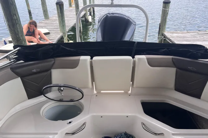 Slide: The Image of 2019 Chaparral 250 Suncoast boat interior at dock, with person sitting nearby. - 28