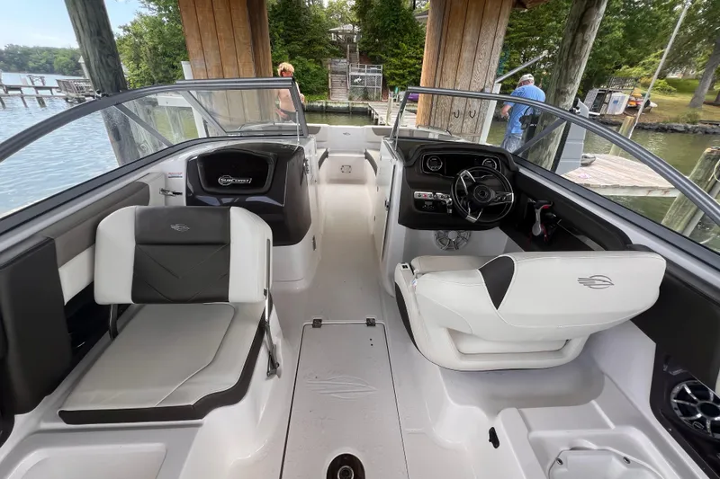 Slide: The Image of 2019 Chaparral 250 Suncoast boat interior with seating and steering wheel, docked by a lake. - 30