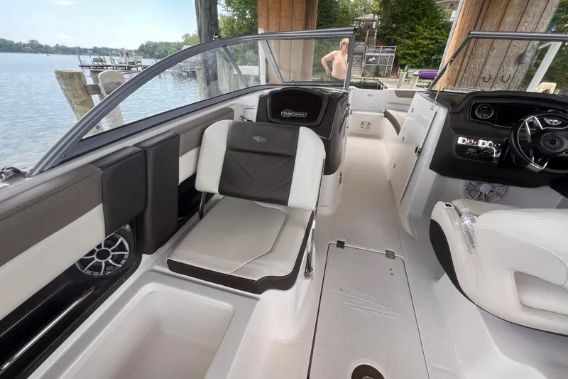 Slide: The Image of 2019 Chaparral 250 Suncoast boat interior with seating and steering wheel, docked by a lake. - 33