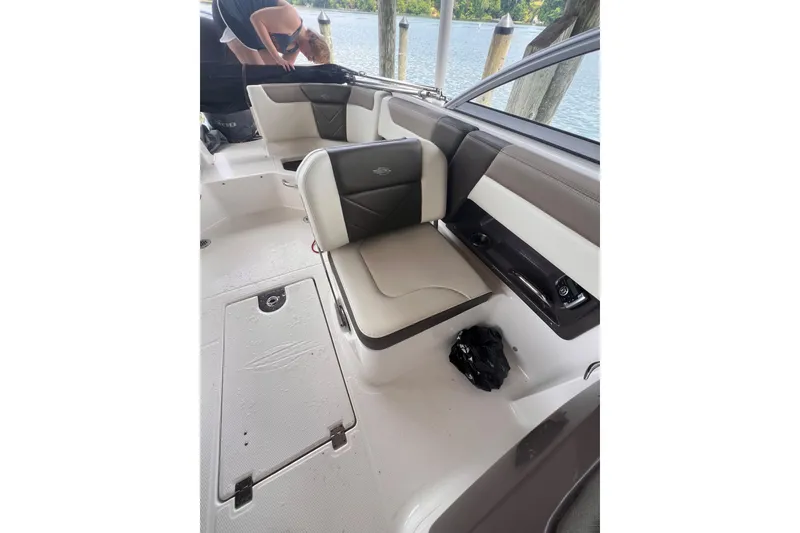 Slide: The Image of 2019 Chaparral 250 Suncoast boat interior with cushioned seating and water view. - 34
