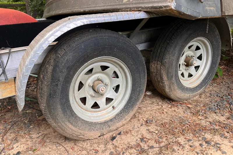 Slide: The Image of Trailer wheels on a Chaparral 250 Suncoast, 2019 model, parked on dirt. - 48