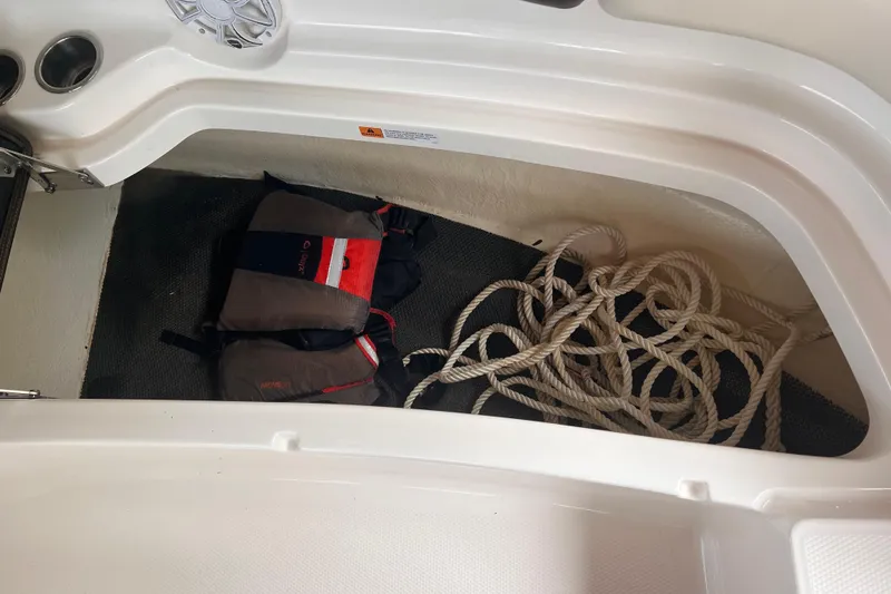 Slide: The Image of Storage compartment in 2019 Chaparral 250 Suncoast boat with life jackets and coiled rope. - 55