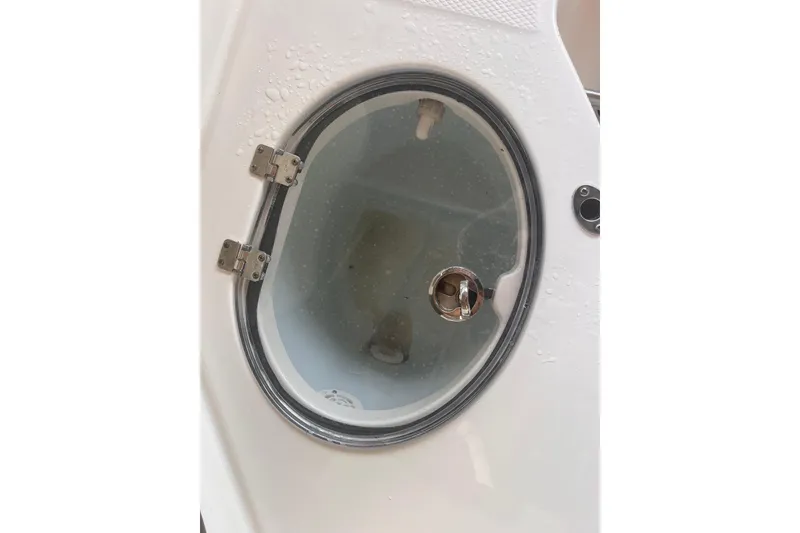 Slide: The Image of 2019 Chaparral 250 Suncoast boat compartment with circular glass cover and metal hinges. - 59