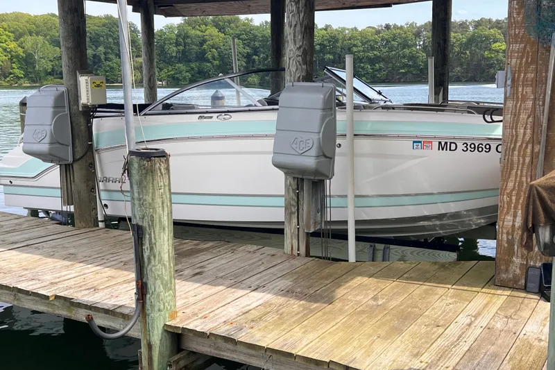 Slide: The Image of 2019 Chaparral 250 Suncoast boat docked on a wooden pier by a serene lake. - 8