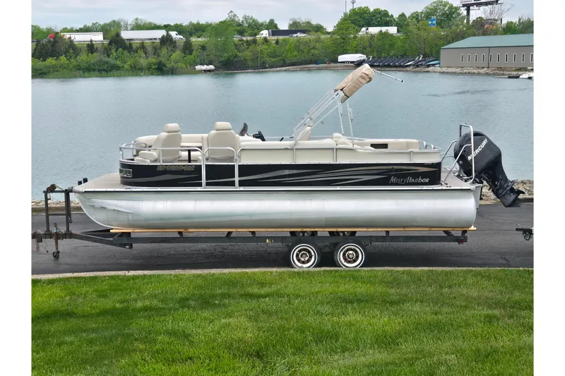 The Image of 2012 Misty Harbor 2285 Biscayne Bay RL pontoon boat on trailer by a lake. - 0