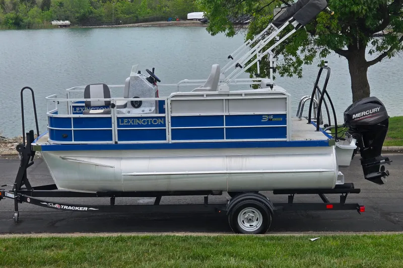 The Image of 2021 Lexington 315 pontoon boat on trailer by a lake. - 0