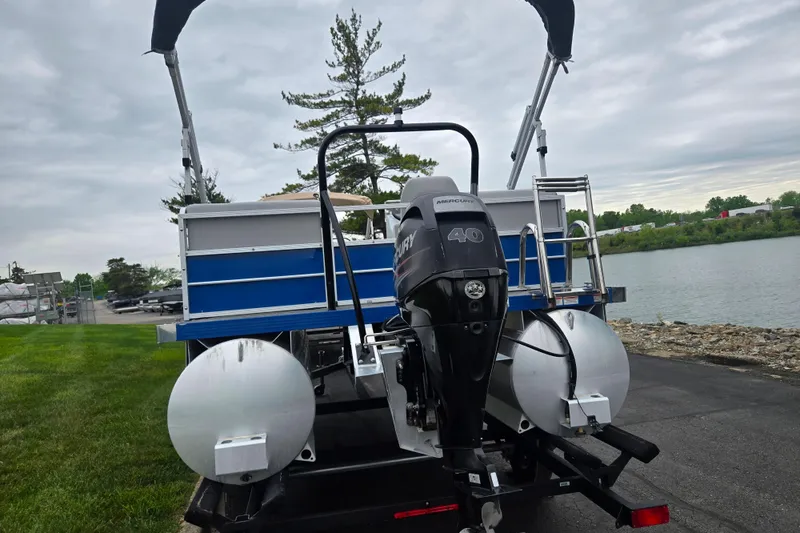 Slide: The Image of 2021 Lexington 315 pontoon boat with Mercury 40 engine by a lakeside. - 2