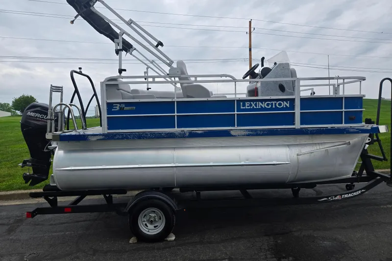Slide: The Image of 2021 Lexington 315 pontoon boat on trailer, featuring blue and silver design. - 4