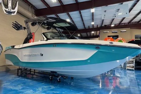 The Image of 2025 MasterCraft XT24 boat in showroom, featuring sleek design and turquoise accents. - 0