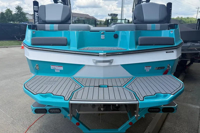 Slide: The Image of 2025 MasterCraft XT24 boat, turquoise and white, rear view with seating and swim platform. - 22