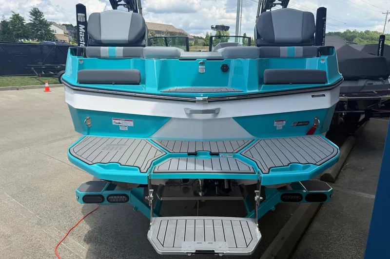 Slide: The Image of 2025 MasterCraft XT24 boat with turquoise and gray seating, displayed outdoors. - 24