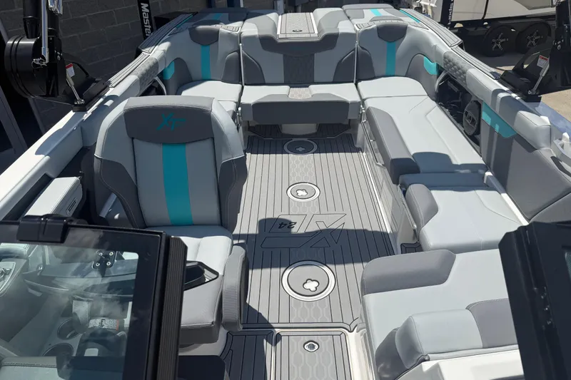 Slide: The Image of 2025 MasterCraft XT24 boat interior with gray and teal seating, showcasing spacious design. - 3