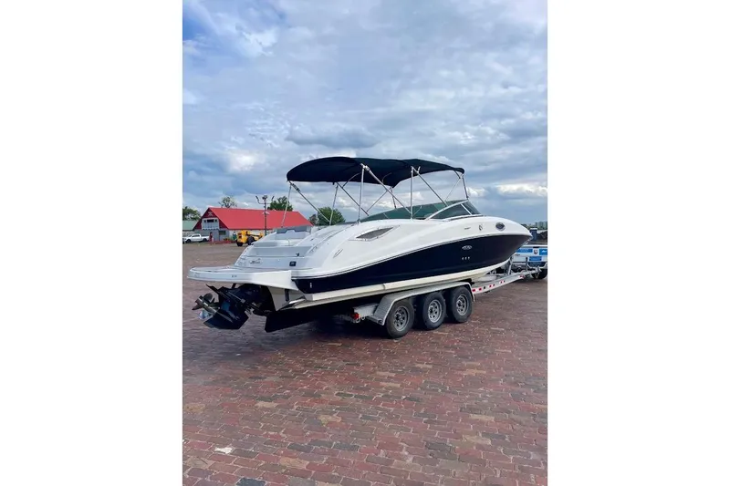 Slide: The Image of 2010 Sea Ray 300 Sundeck boat on trailer, parked on brick pavement under cloudy sky. - 3