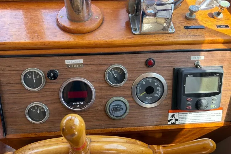 Slide: The Image of 1976 Grand Banks 32 Sedan dashboard with gauges and controls, featuring a wooden steering wheel. - 17