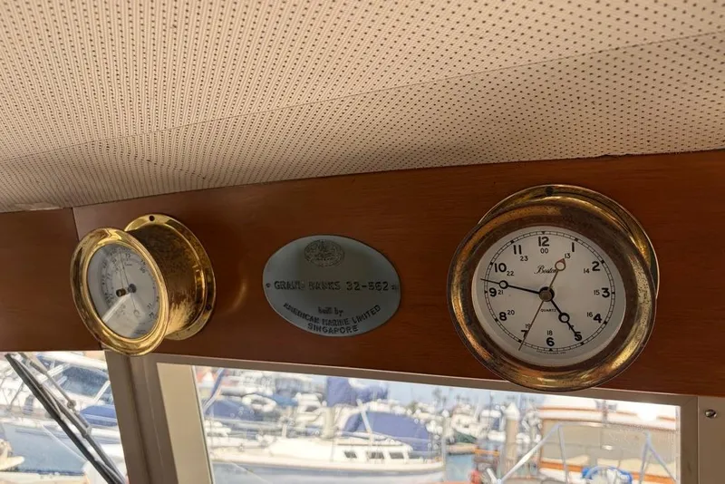 Slide: The Image of 1976 Grand Banks 32 Sedan interior with brass clock and barometer, marina view. - 23