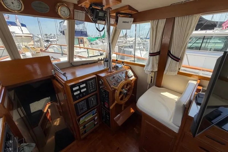 Slide: The Image of 1976 Grand Banks 32 Sedan interior with wooden helm, gauges, and marina view. - 24
