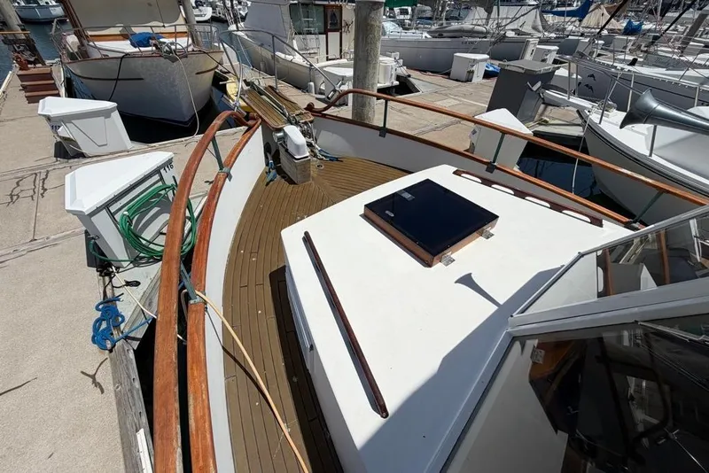 Slide: The Image of 1976 Grand Banks 32 Sedan boat docked at marina, featuring wooden deck and railing. - 4