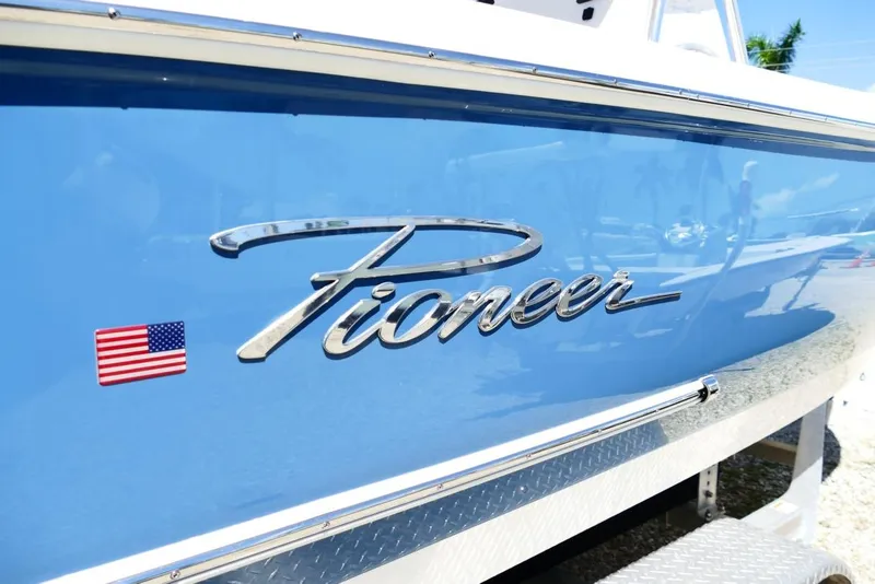 Slide: The Image of 2026 Pioneer 222 Islander boat with American flag emblem on blue hull. - 2