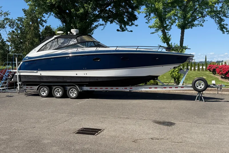 The Image of 2004 Cobalt 360 boat on trailer, parked outdoors with trees and flowers in the background. - 0
