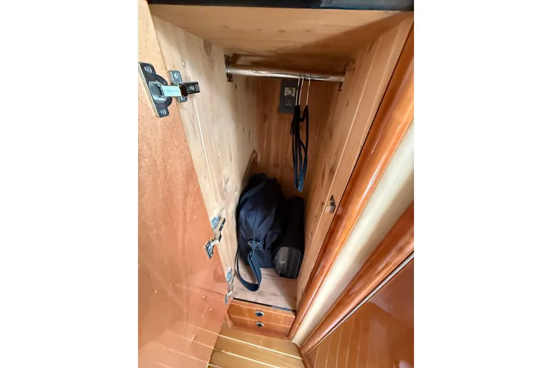 Slide: The Image of Wooden closet interior on a 2004 Cobalt 360 boat, featuring hangers and a bag. - 14