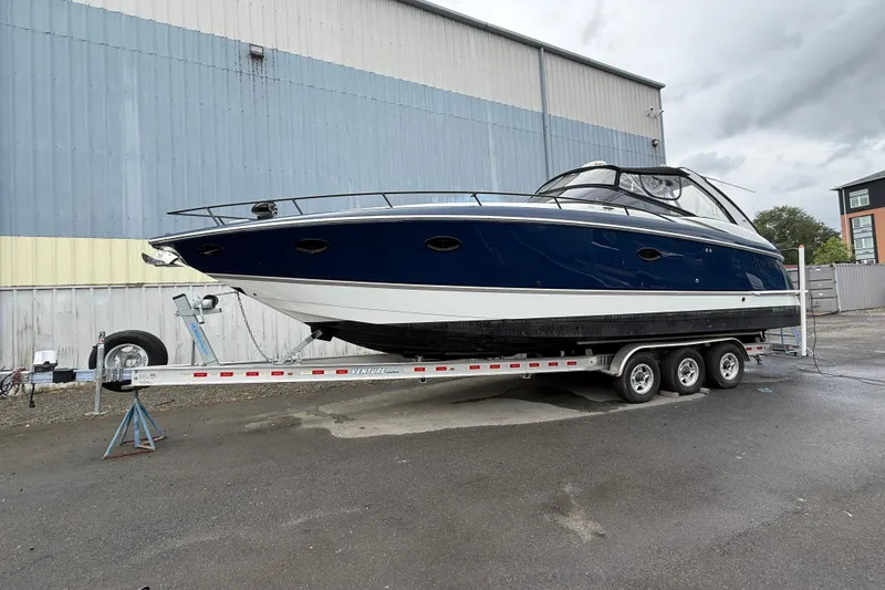 Slide: The Image of 2004 Cobalt 360 boat on trailer, parked outdoors near industrial building. - 2