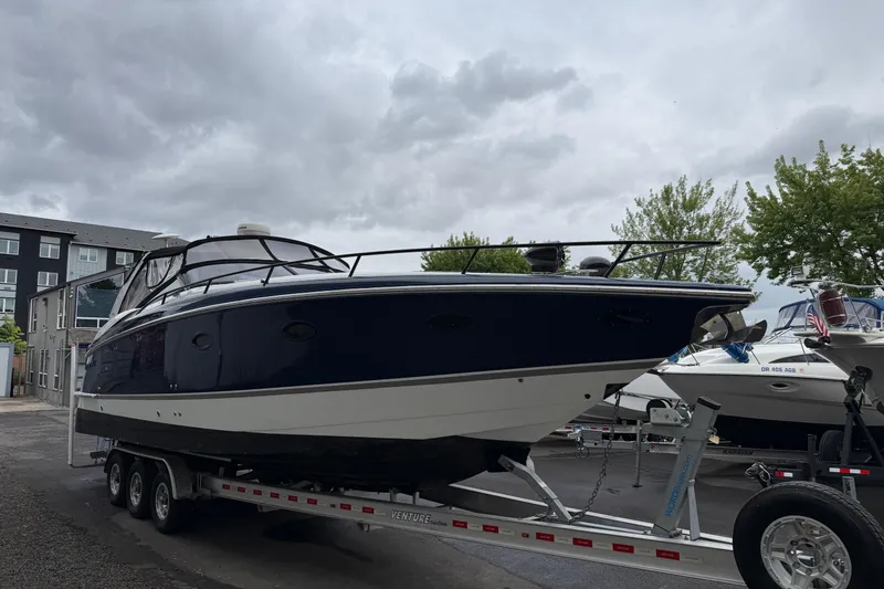 Slide: The Image of 2004 Cobalt 360 boat on trailer under cloudy sky, parked near buildings and trees. - 5