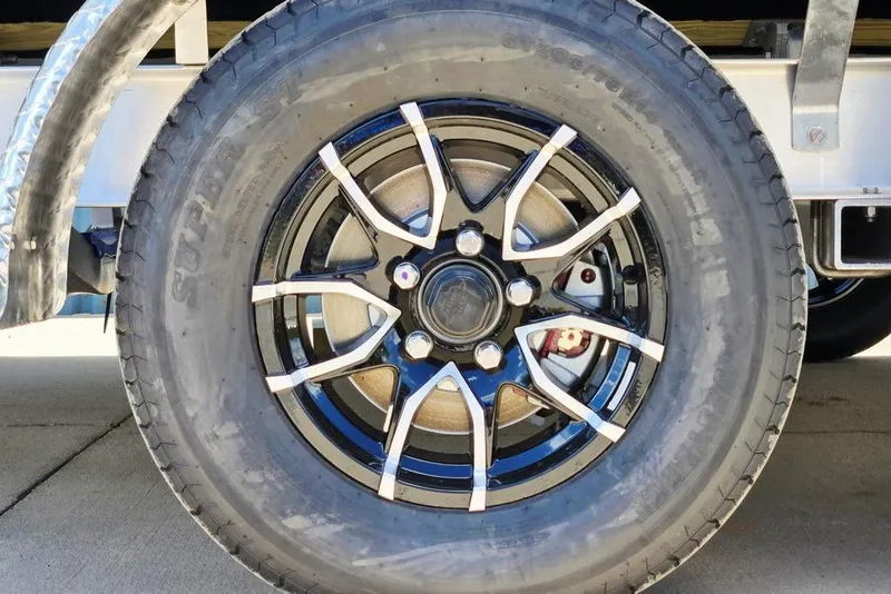 Slide: The Image of Close-up of a 2026 Tidewater 2210 Carolina Bay trailer wheel with stylish black and silver rim. - 48