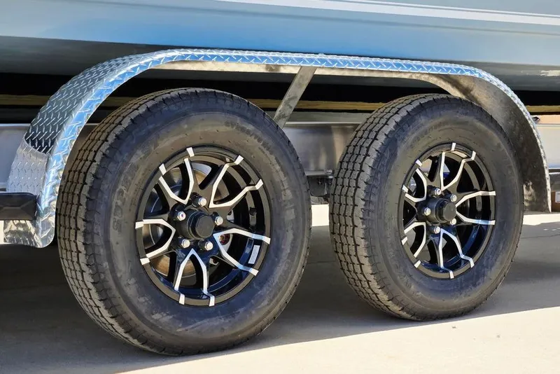 Slide: The Image of Trailer wheels of a 2026 Tidewater 2210 Carolina Bay boat, featuring stylish black rims. - 49