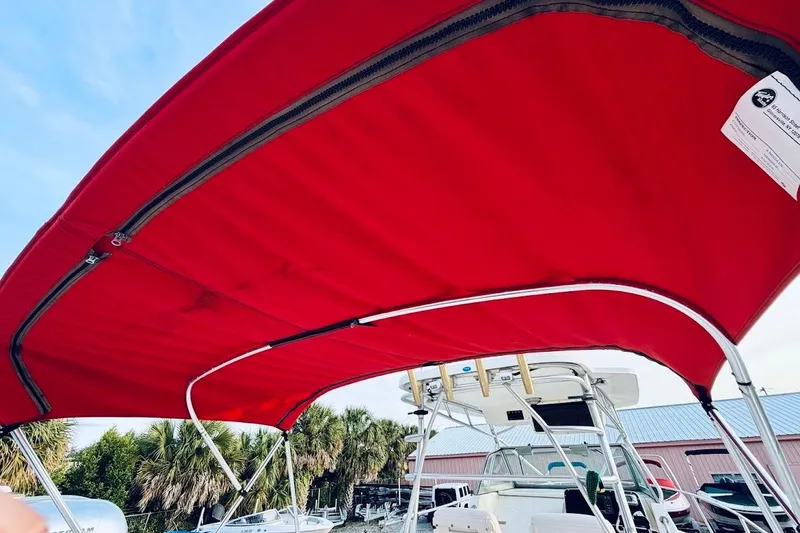 Slide: The Image of Red canopy on a 2002 Boston Whaler 290 Outrage boat, with palm trees in background. - 21