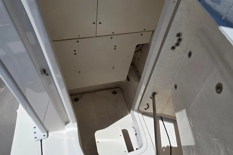 Slide: The Image of 2024 Robalo 246 Cayman interior storage compartment with white finish and secure fittings. - 16