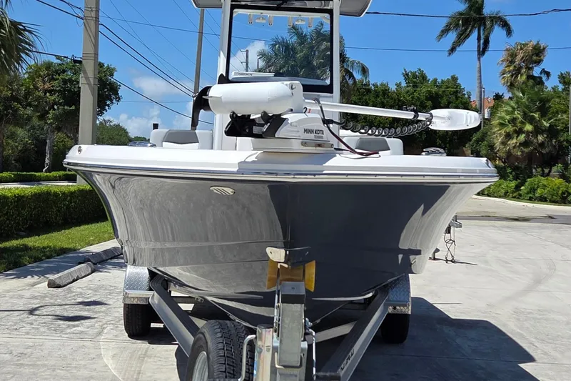 Slide: The Image of 2024 Robalo 246 Cayman boat on trailer, parked outdoors under clear blue sky. - 2