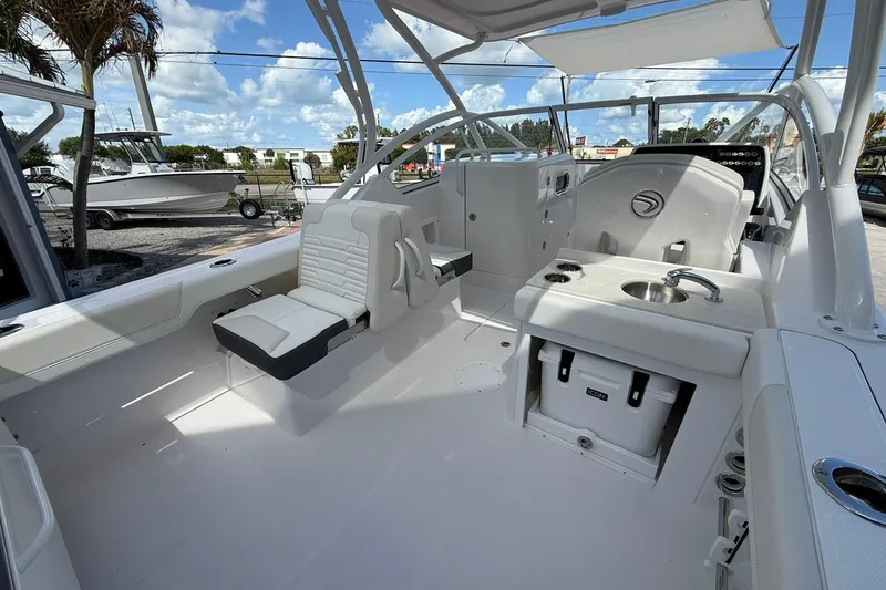 Slide: The Image of 2026 Edgewater 248CX Crossover boat interior with seating and sink under a sunny sky. - 10