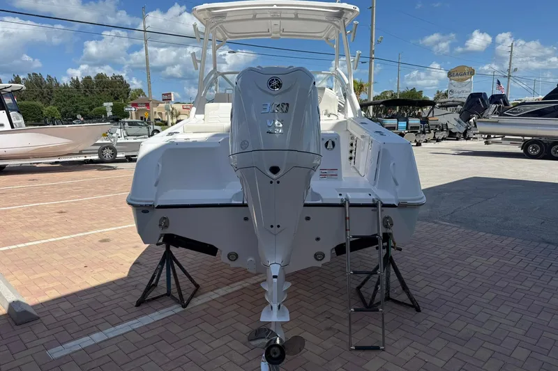 Slide: The Image of 2026 Edgewater 248CX Crossover boat with powerful outboard motor in a sunny marina. - 2