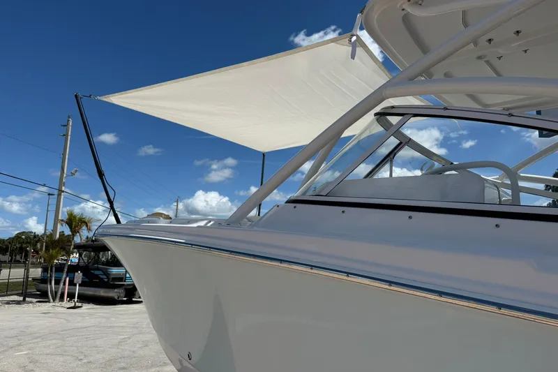 Slide: The Image of 2026 Edgewater 248CX Crossover boat with sunshade, parked under a clear blue sky. - 4