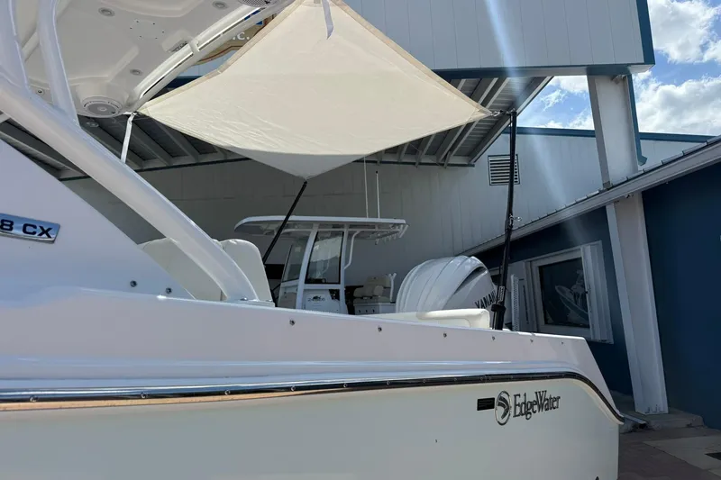 Slide: The Image of 2026 Edgewater 248CX Crossover boat with canopy, displayed outdoors under a blue sky. - 5