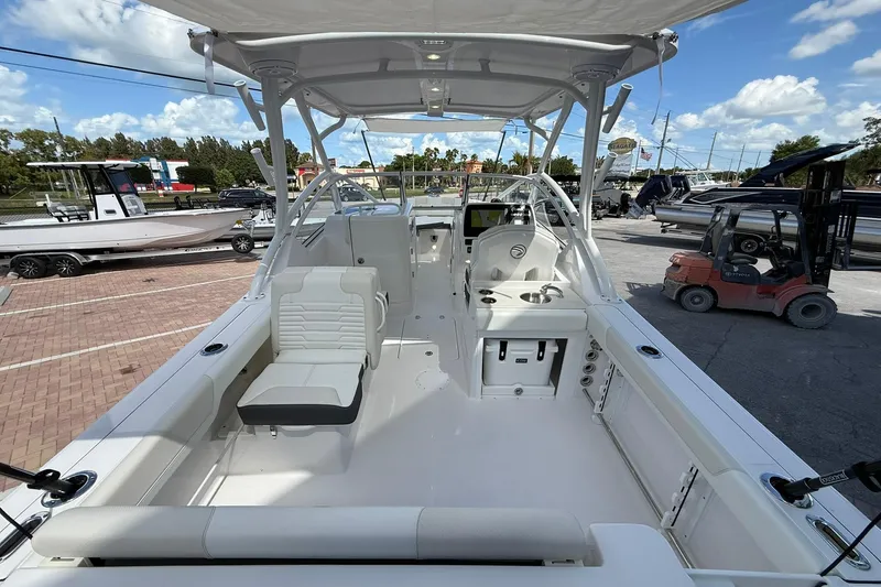 Slide: The Image of 2026 Edgewater 248CX Crossover boat interior with seating and helm, parked outdoors. - 8