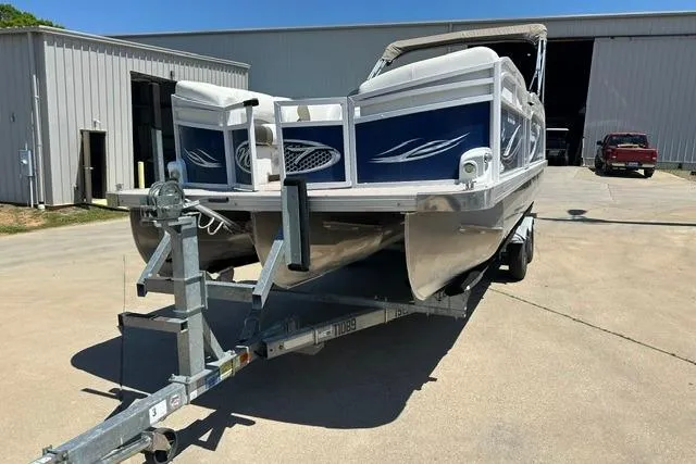 The Image of 2013 JC 23 Neptoon TT pontoon boat on trailer outside a warehouse. - 1